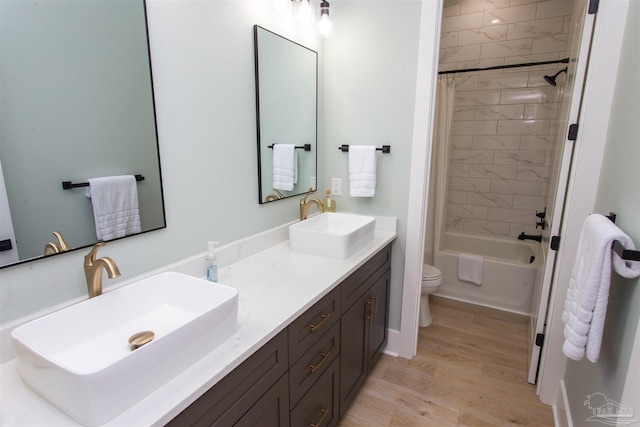 bathroom featuring double vanity, toilet, shower / bathtub combination with curtain, and a sink