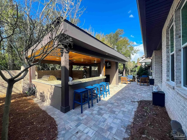 view of patio / terrace featuring an outdoor living space, outdoor wet bar, an outdoor kitchen, and fence