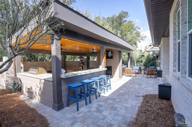 view of patio featuring area for grilling, fence, outdoor wet bar, an outdoor hangout area, and an outdoor kitchen