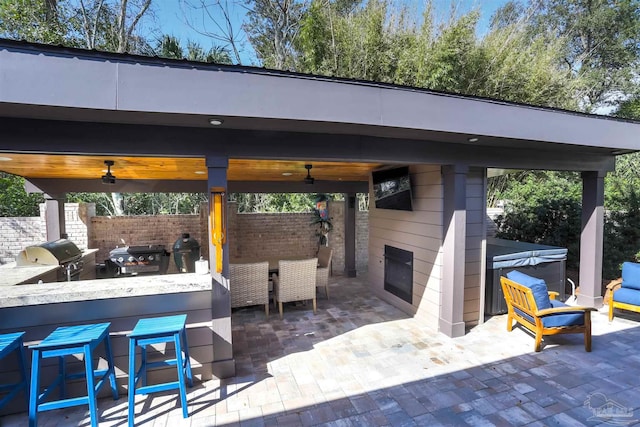 view of patio / terrace with outdoor wet bar, area for grilling, a hot tub, and a grill