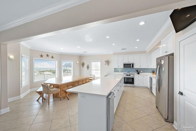 kitchen featuring white cabinets, appliances with stainless steel finishes, a kitchen island, ornamental molding, and light tile patterned floors