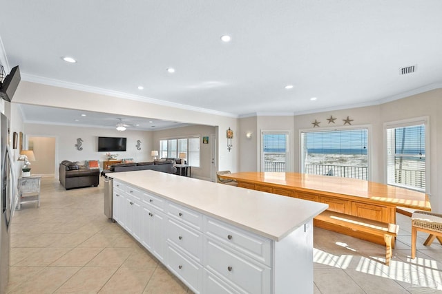 kitchen featuring white cabinets, a center island, light tile patterned floors, and plenty of natural light