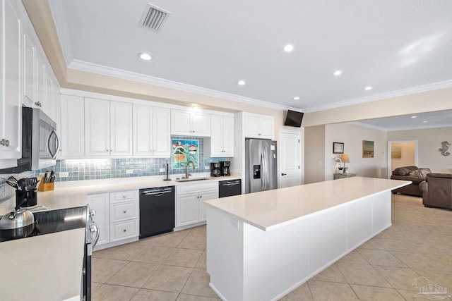 kitchen with appliances with stainless steel finishes, sink, white cabinetry, light tile patterned flooring, and a center island