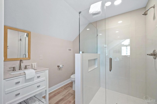 bathroom with toilet, hardwood / wood-style flooring, vanity, a shower with door, and lofted ceiling