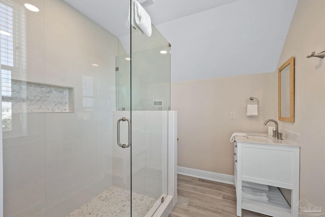 bathroom featuring wood-type flooring, walk in shower, lofted ceiling, and vanity