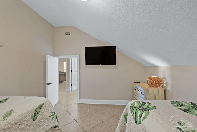 bedroom featuring a textured ceiling, light tile patterned floors, and vaulted ceiling