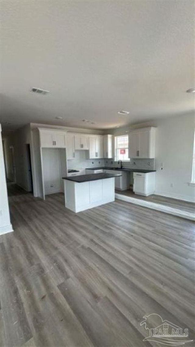 2116 W De Soto St, Pensacola, FL 32505 - kitchen featuring a kitchen island, white cabinetry, dark countertops, and wood finished floors