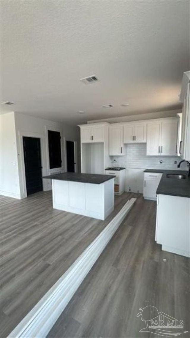 2116 W De Soto St, Pensacola, FL 32505 - kitchen with dark countertops, a sink, a textured ceiling, white cabinetry, and dark wood-type flooring