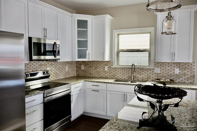 kitchen featuring tasteful backsplash, light stone counters, stainless steel appliances, sink, and white cabinetry