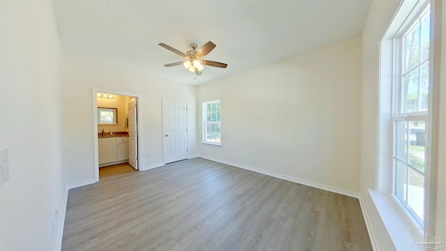 unfurnished bedroom with white fridge, light hardwood / wood-style flooring, ensuite bath, and ceiling fan