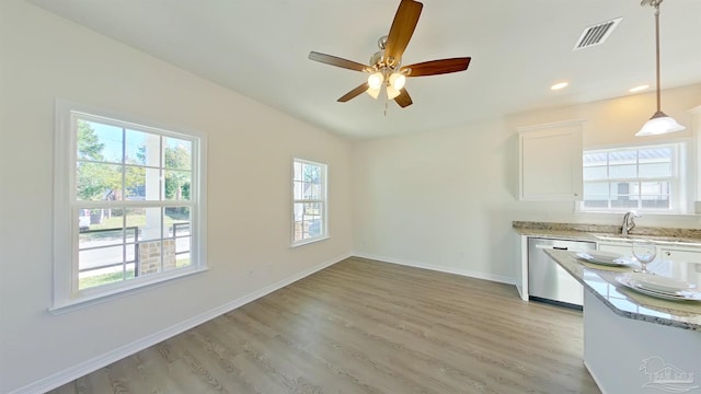 kitchen with sink, stainless steel dishwasher, light wood-type flooring, decorative light fixtures, and white cabinetry