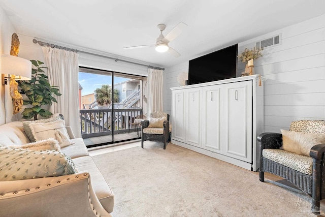 living room with light colored carpet, ceiling fan, and wooden walls