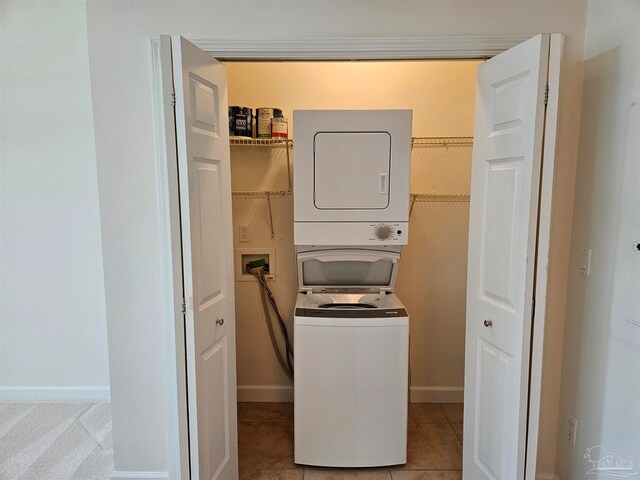 clothes washing area with stacked washer / dryer and light tile patterned flooring