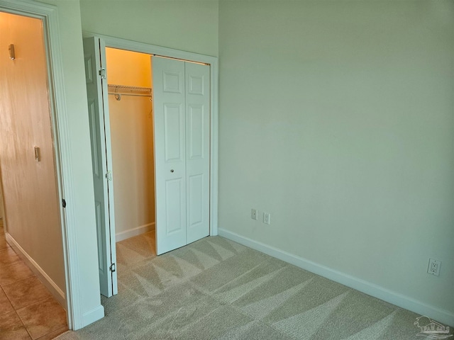 unfurnished bedroom featuring light carpet and a closet