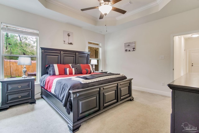 bedroom featuring baseboards, ornamental molding, a raised ceiling, and light colored carpet