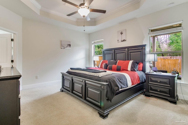 bedroom with light carpet, a tray ceiling, baseboards, and crown molding