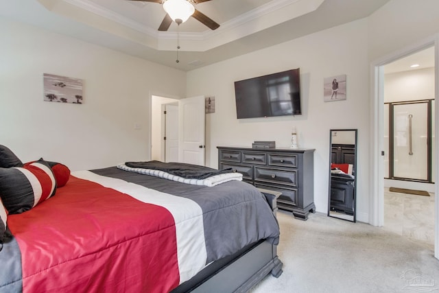 bedroom featuring light carpet, a tray ceiling, ensuite bathroom, and crown molding