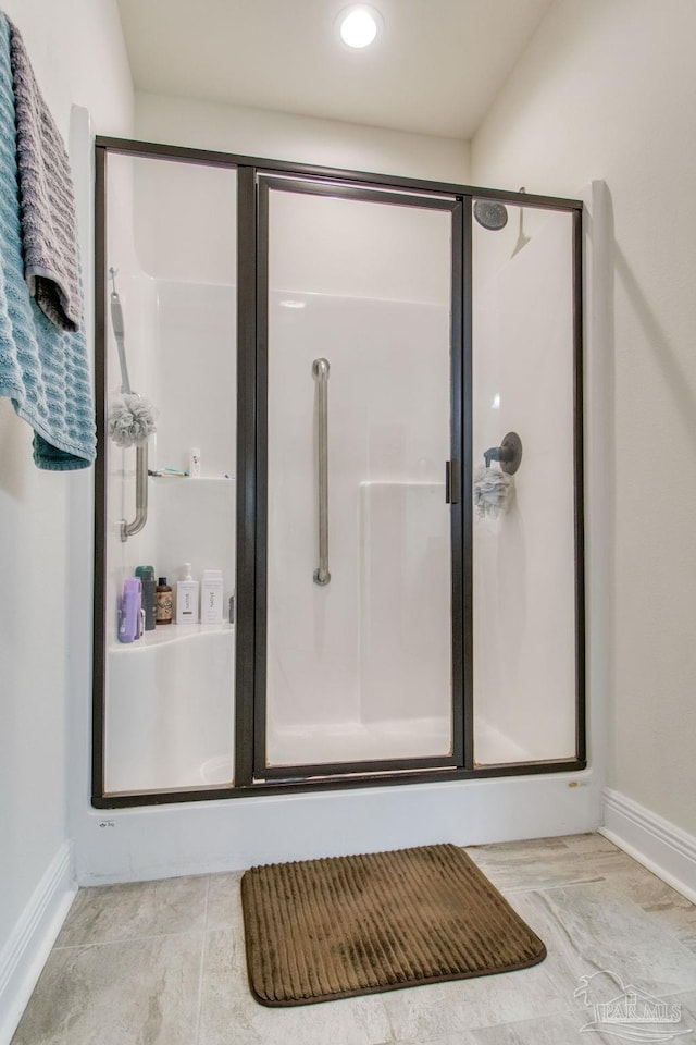 bathroom with a stall shower and baseboards