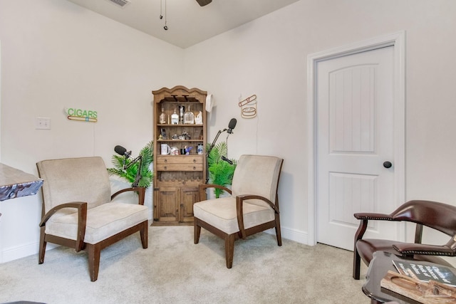 sitting room with a ceiling fan, light colored carpet, visible vents, and baseboards