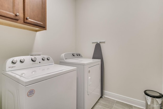 clothes washing area featuring cabinet space, independent washer and dryer, and baseboards