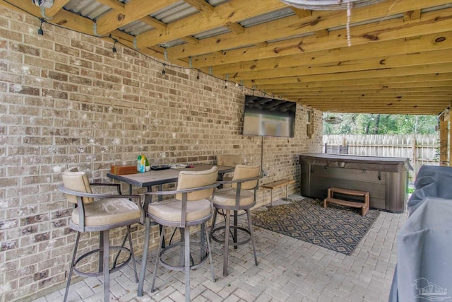 view of patio featuring outdoor dining space, fence, and a hot tub