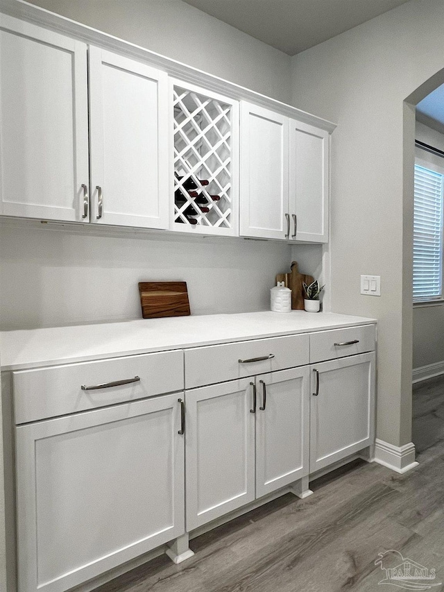 bar featuring wood-type flooring and white cabinetry