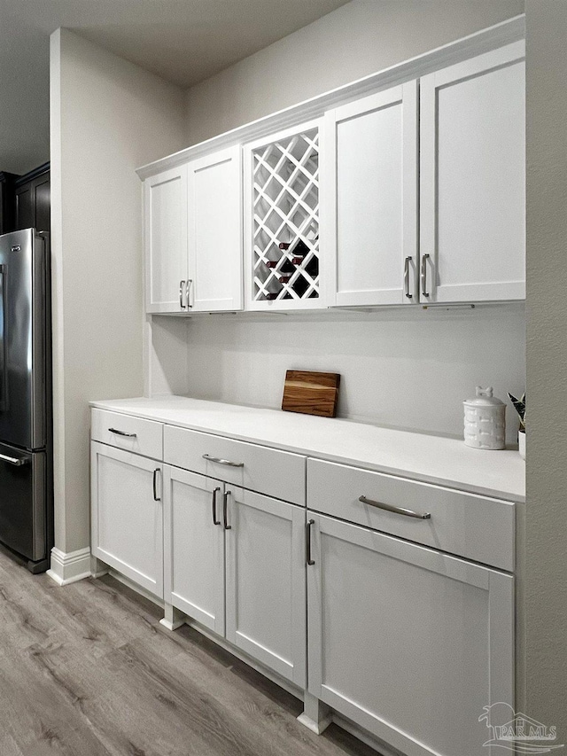 interior space with white cabinets, light wood-type flooring, and stainless steel fridge