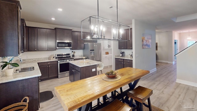 kitchen featuring a center island, sink, light wood-type flooring, stainless steel appliances, and dark brown cabinets