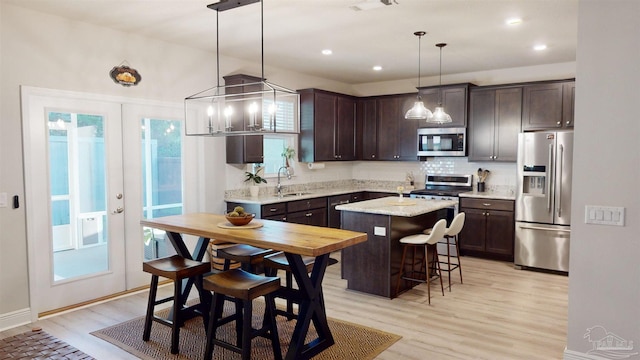 kitchen featuring pendant lighting, a kitchen island, sink, appliances with stainless steel finishes, and dark brown cabinets