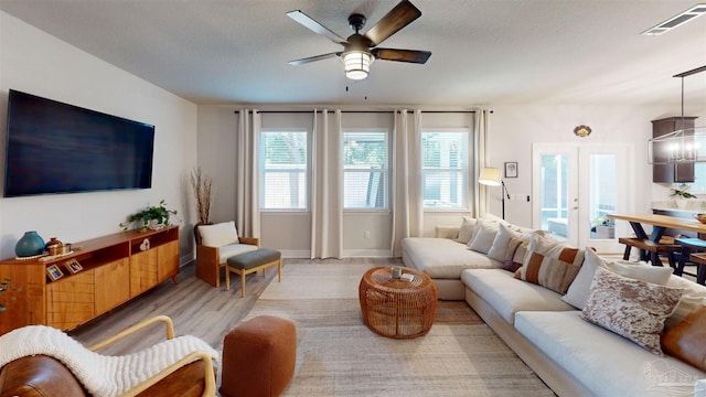 living room featuring a textured ceiling, ceiling fan, light hardwood / wood-style floors, and french doors