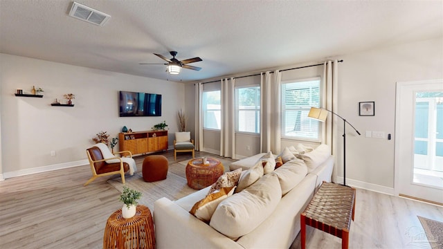 living room with a textured ceiling, ceiling fan, and light hardwood / wood-style flooring