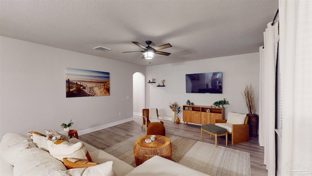 living room featuring a textured ceiling, ceiling fan, and wood-type flooring