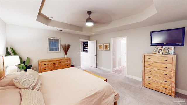 bedroom featuring ceiling fan, connected bathroom, a raised ceiling, and carpet floors