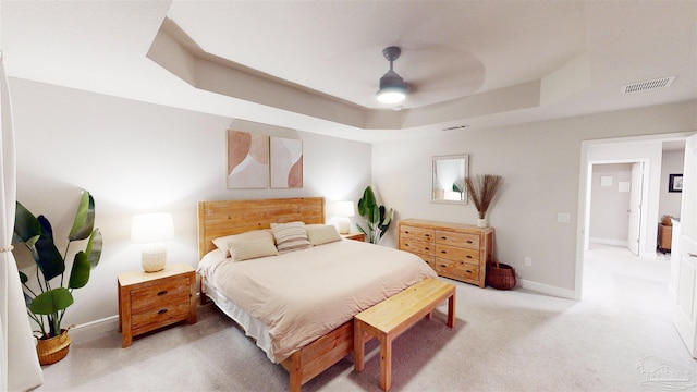 bedroom featuring ceiling fan, light colored carpet, and a raised ceiling