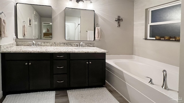 bathroom with a washtub, wood-type flooring, and vanity