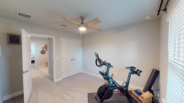 exercise room with ceiling fan and light carpet