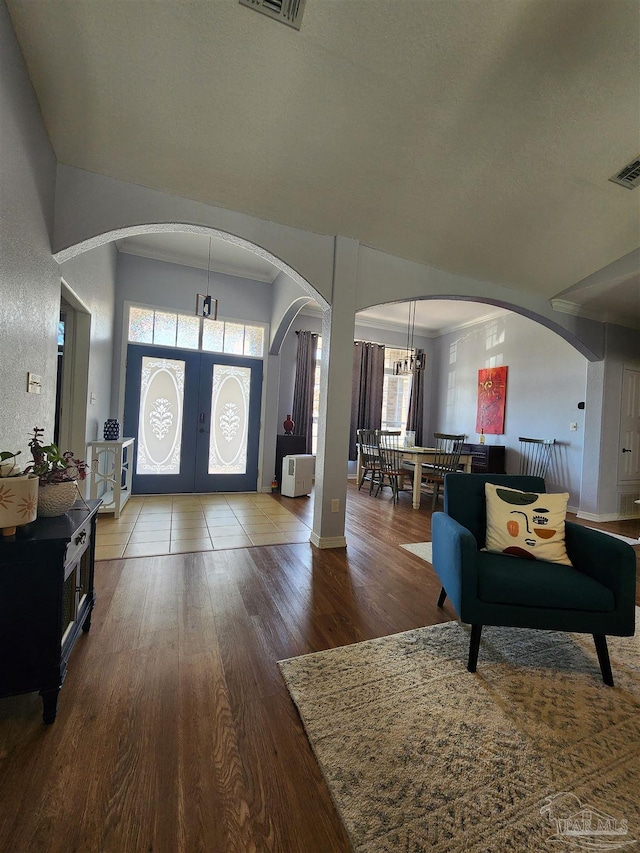 entrance foyer featuring crown molding, a healthy amount of sunlight, a chandelier, and hardwood / wood-style floors