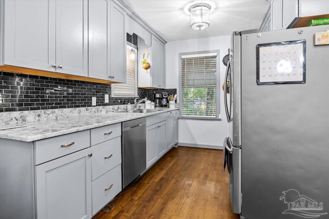 kitchen featuring appliances with stainless steel finishes, light stone counters, gray cabinetry, sink, and dark hardwood / wood-style floors