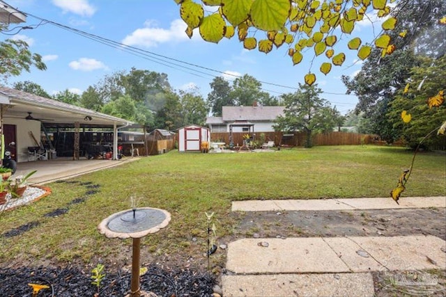 view of yard with ceiling fan, a shed, and a patio area