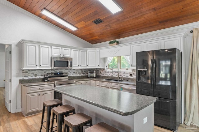 kitchen with appliances with stainless steel finishes, dark countertops, lofted ceiling, wood ceiling, and a sink