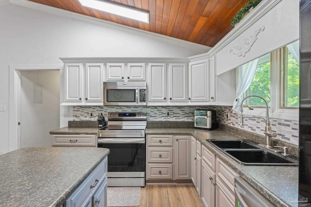 kitchen featuring dark countertops, a sink, vaulted ceiling, and stainless steel appliances