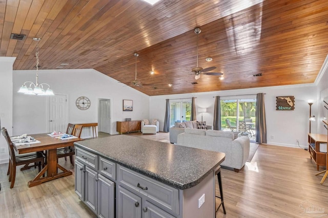 kitchen featuring gray cabinets, dark countertops, light wood-style floors, and lofted ceiling