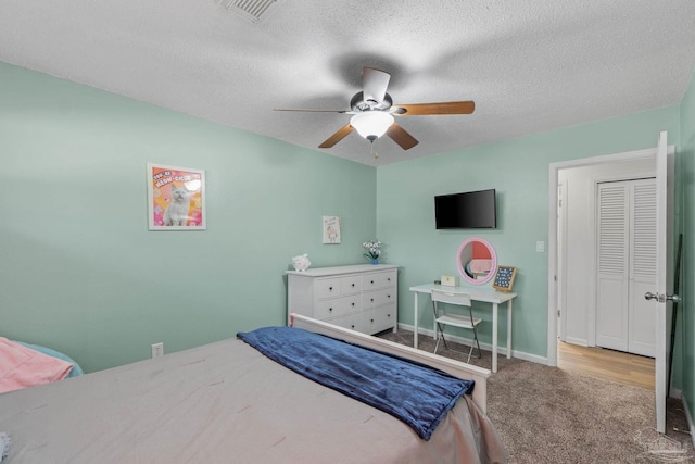 carpeted bedroom with visible vents, baseboards, a ceiling fan, and a textured ceiling