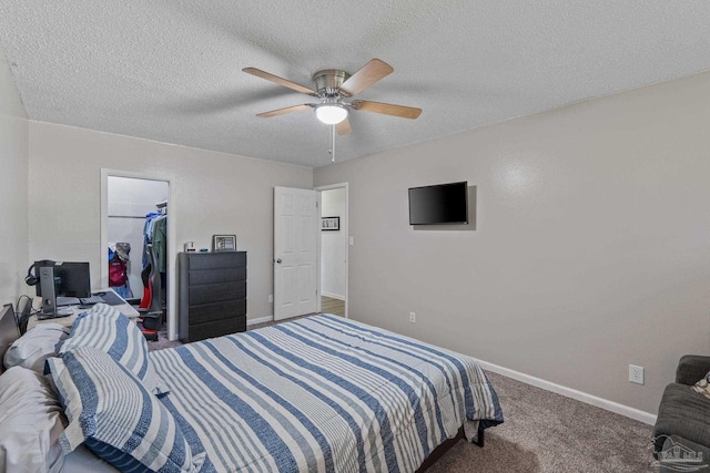 carpeted bedroom featuring a closet, baseboards, a spacious closet, a ceiling fan, and a textured ceiling