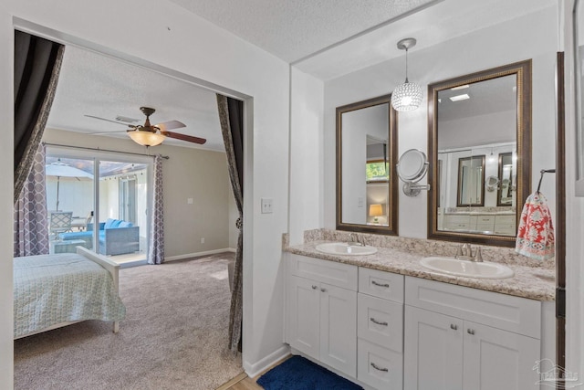 ensuite bathroom with a sink, ensuite bathroom, ceiling fan, and a textured ceiling