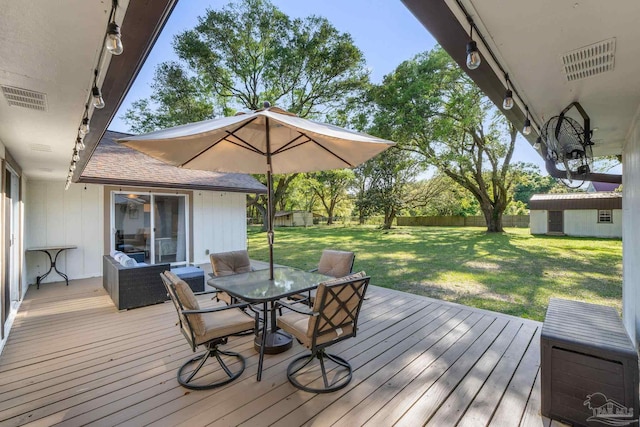 deck featuring a yard, a fenced backyard, an outdoor structure, visible vents, and outdoor dining area