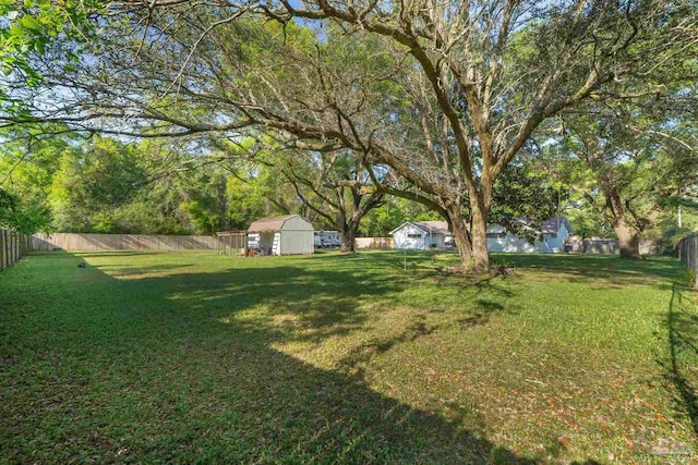 view of yard featuring a fenced backyard, an outdoor structure, and a storage unit