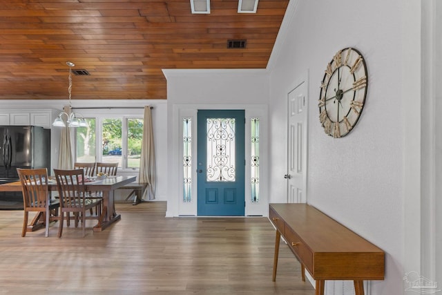 foyer entrance featuring an inviting chandelier, crown molding, visible vents, wood ceiling, and wood finished floors