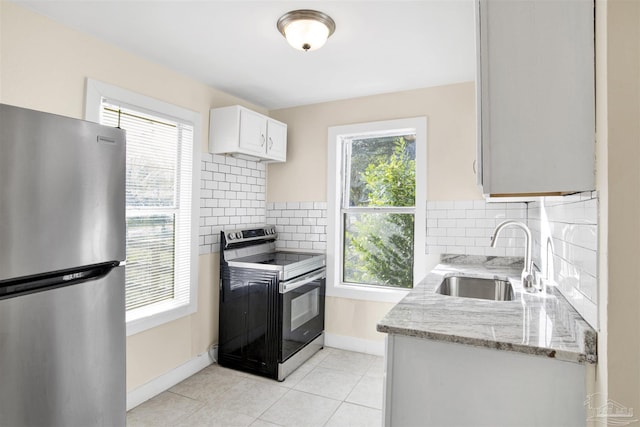 kitchen featuring a healthy amount of sunlight, appliances with stainless steel finishes, white cabinets, and a sink