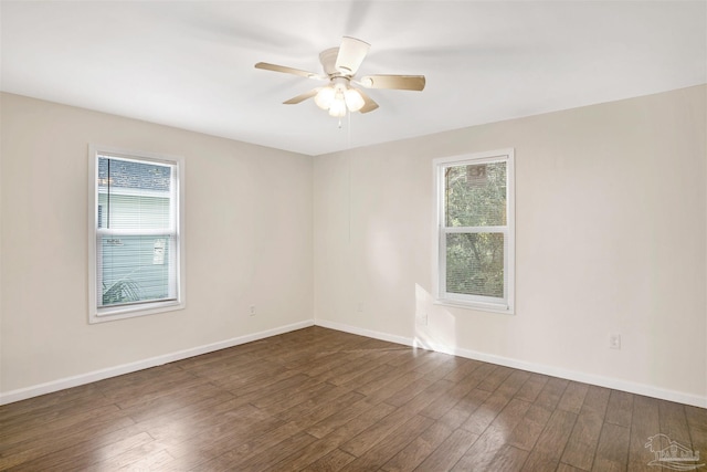 unfurnished room with dark wood-style flooring, a healthy amount of sunlight, ceiling fan, and baseboards